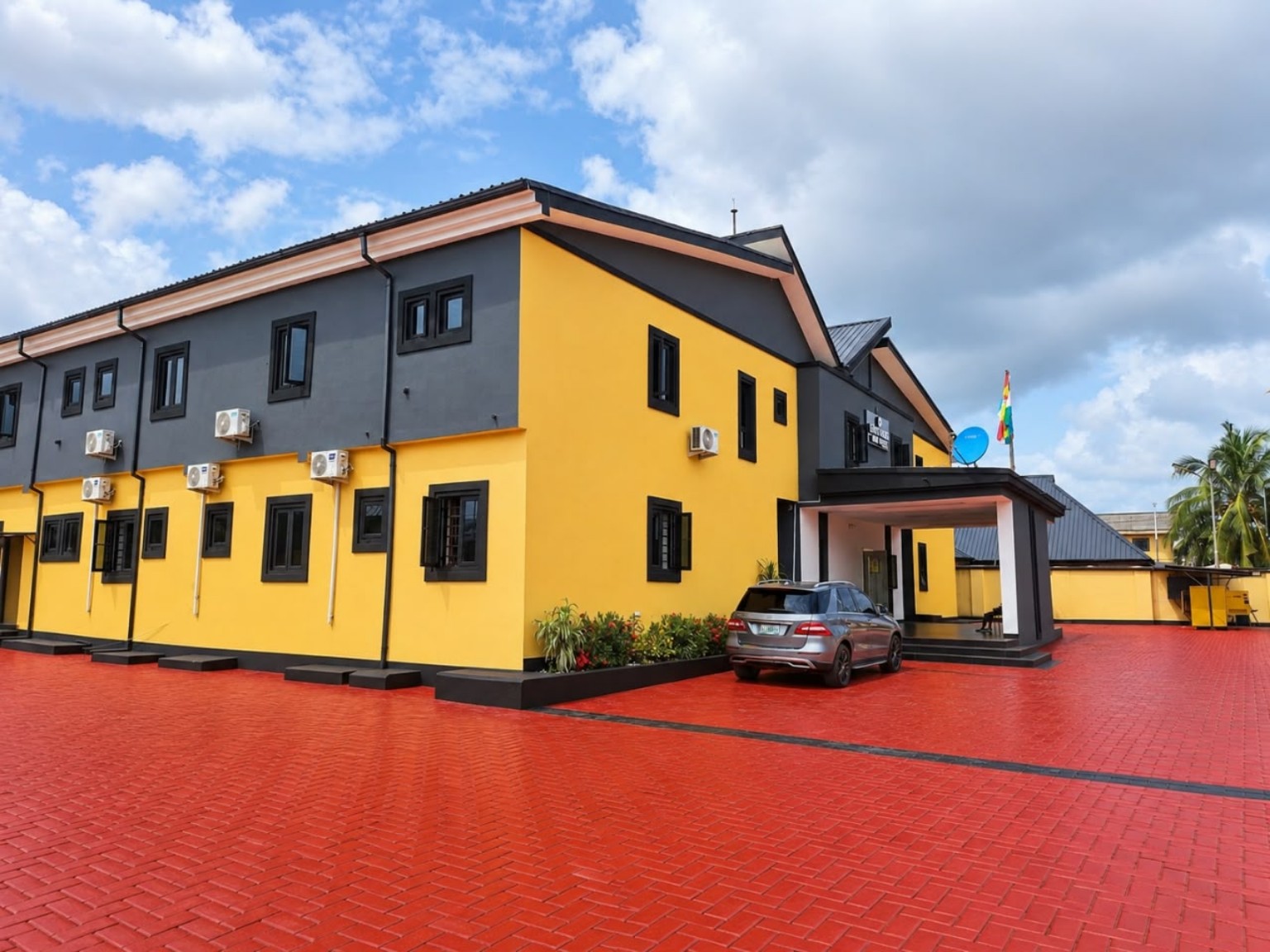 Exterior view of Lloyd Hotel, with yellow and charcoal walls and a spacious paved forecourt